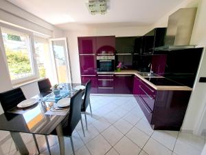 a kitchen with purple cabinets and a table with chairs at Apartman Koli Opatija in Opatija