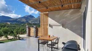 a table and chairs on a patio with mountains in the background at Gratelia Apartment Damnoni in Dhamnóni