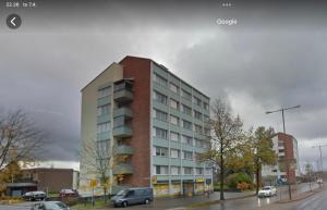 a building on a street with cars parked in a parking lot at 6. kerroksen yksiö lähellä matkakeskusta. in Lappeenranta