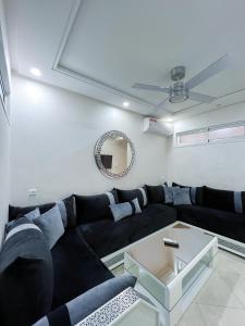 a living room with a black couch and a mirror at Rif Appartment in Al Hoceïma +31 photos