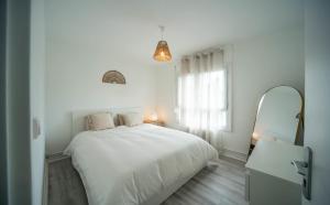 1 dormitorio blanco con 1 cama grande y espejo en La vie en Beige - Appartement à Chalon-sur-Saône, en Chalon-sur-Saône