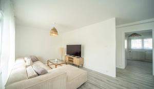 sala de estar blanca con sofá y TV en La vie en Beige - Appartement à Chalon-sur-Saône, en Chalon-sur-Saône