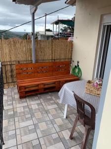 un banc en bois assis sur une terrasse avec une table dans l'établissement KONTI VILLA, à Kondáraina
