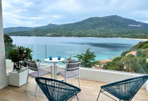 a balcony with a table and chairs and a view of the water at Miramar Corsica in Propriano