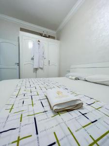 a white bedroom with a white shirt on a bed at Rif Appartment in Al Hoceïma