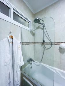 a bathroom with a shower and a white robe at Rif Appartment in Al Hoceïma
