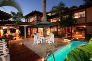 a house with a pool and chairs and an umbrella at Pousada Vila do Mar in Búzios