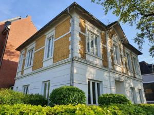 a large white house with windows and bushes at Wohnen in der Bürgermeistervilla in Hamburg