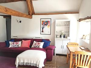 a living room with a purple couch and a table at Old Bake House Cottage @ Cwm Mill in Michaelchurch Escley
