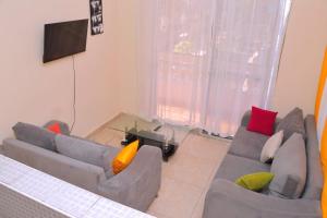 Una sala de estar con dos sofás y un televisor de pantalla plana. en Home Away from Home, en Mombasa