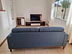 a blue couch in a living room with a tv at Casa espaçosa em Poços de Caldas in Poços de Caldas