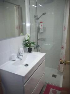 une salle de bain blanche avec un lavabo et une douche dans l'établissement Appartement Decathlon Salou, à Salou