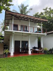 a large white house with a balcony on top of it at Beach House Kalukatiya - Family Villa, Seaview Room, Garden Room in Dickwella