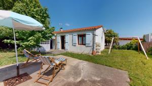 Un par de sillas y una sombrilla frente a una casa. en La Dolce Vita proche des plages, en Saint-Hilaire-de-Riez