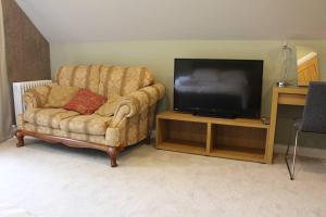 a living room with a chair and a flat screen tv at Boutique double room with countryside views in Wilby