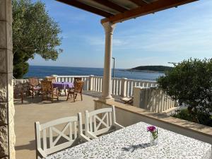 een tafel en stoelen op een balkon met uitzicht op de oceaan bij Villa Porthos in Hvar