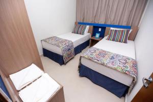 a small room with two beds and a door at Apartamento 2 quartos Lazer Completo in Caldas Novas