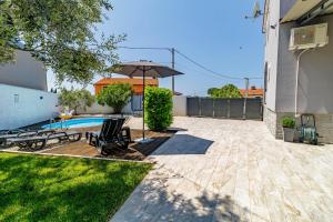 a backyard with a swimming pool and an umbrella at Holiday House Ulika in Marčana