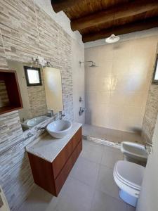 a bathroom with two sinks and a toilet and a mirror at Los Aromos'home in Chacras de Coria