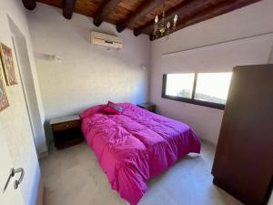 a bedroom with a pink bed and a window at Los Aromos'home in Chacras de Coria