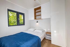 een witte slaapkamer met een bed en een raam bij Domki Letniskowe Plaża II in Sianozety