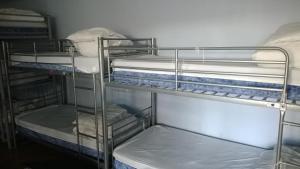 a room with three bunk beds with white sheets at Queen Elizabeth Hostel in London