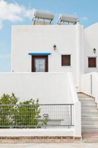 a white building with stairs and a fence at Το Μεγάλο Αμπέλι in Megalokhori