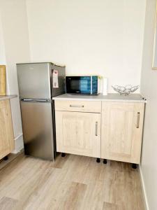 a kitchen with a stainless steel refrigerator and a microwave at Studio centre-ville au calme in Espalion