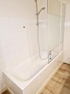 a white bathroom with a shower and a tub at Studio centre-ville au calme in Espalion