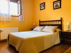 a bedroom with a bed with yellow walls and a window at Hostal La Serna in Potes