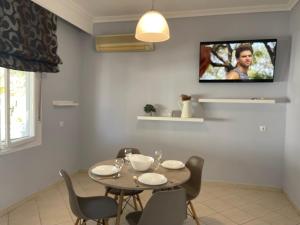 comedor con mesa y sillas y TV en la pared en Seabayhome en Néa Péramos