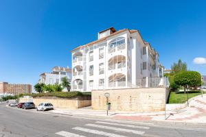 biały budynek po stronie ulicy w obiekcie APARTAMENTO VACACIONAL A 10 MIN PUERTO DE BENALMADENA Y LA CARIHUELA PISCINA PLAYA PARKING GRATIS w mieście Torremolinos
