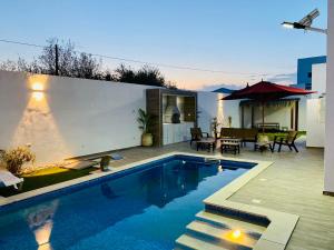 a swimming pool in a backyard with a table and chairs at Super villa midoun in Djerba