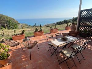 un patio con mesa, sillas y el océano en B&B La Torre en Realmonte