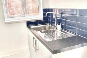 a kitchen with a stainless steel sink and blue tiles at Modern 2 bed flat in Moseley in Birmingham