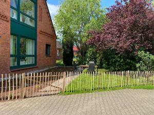 a fence in front of a brick building with a bench at Ferienwohnung Garten Eben in Rullstorf