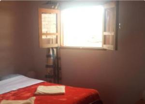 um quarto com uma cama com um cobertor vermelho e uma janela em Auberge Village Paradise Valley em Tagherat Anekrim