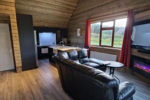 a living room with a leather couch and a table at MT. Leinster View Cabin in Enniscorthy