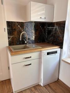 a white kitchen with a sink and a dishwasher at Dom Nad Jeziorem Trzy Tonie in Silna Nowa