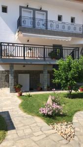 a house with a balcony and a yard with flowers at Savvas House in Neos Marmaras