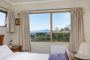 a bedroom with a bed and a large window at Harbour View Guesthouse in Auckland