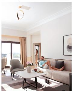 un homme assis sur un canapé dans un salon dans l'établissement Address Marassi Golf Resort Hotel Appartments, à El Alamein