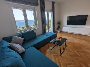 a living room with a blue couch and a flat screen tv at Apartment Arya in Crikvenica