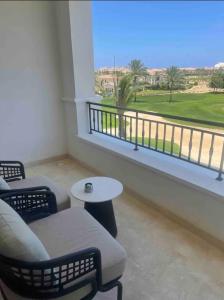 Habitación con balcón con sillas y mesa. en Address Marassi Golf Resort Hotel Appartments en El Alamein