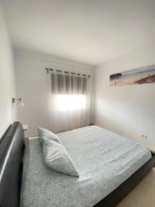 a white bedroom with a bed and a window at APARTAMENTO EN LOS CRISTIANOS - FREE WIFI in Los Cristianos