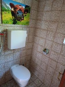 La salle de bains est pourvue de toilettes et d'une photo d'une vache. dans l'établissement Kuhstall Appartement, à Weiler