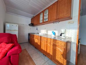 cocina con armarios de madera y sofá rojo en Apartman Tea, en Novi Vinodolski