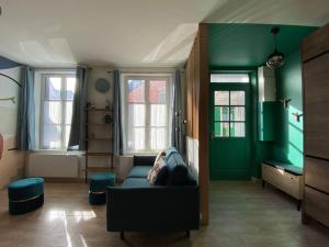 Luminieuse maison de pêcheur avec terrasse في سانت فاليري سور سوم: غرفة معيشة بجدران خضراء وأريكة زرقاء