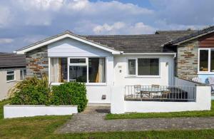una casa blanca con una mesa delante en Comfortable bungalow near Widemouth Bay beach, en Poundstock