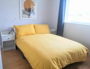 1 cama amarilla en un dormitorio con ventana en Comfortable bungalow near Widemouth Bay beach, en Poundstock